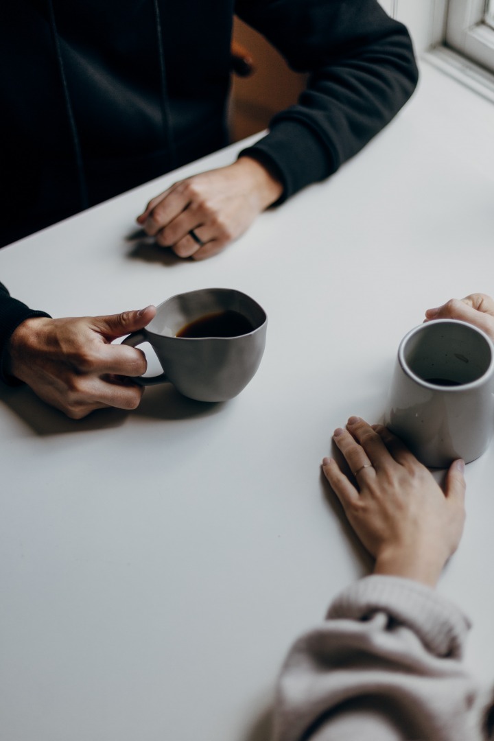 Hands on the table holding cups of coffee