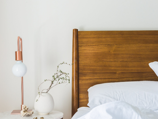 White walls with a pine bed in front of if with white bedsheets on