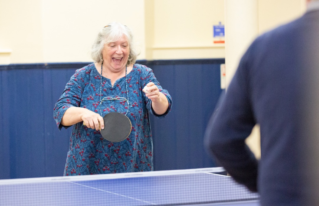 A woman playing table tennis smiling