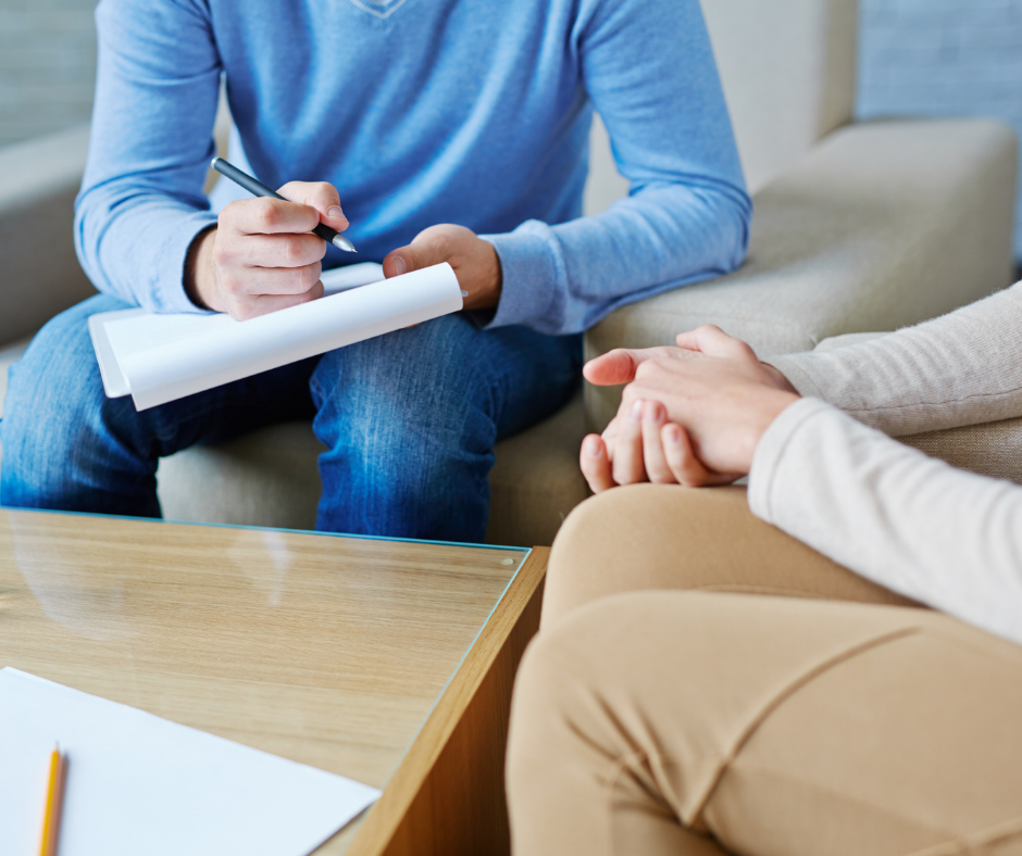 two people at down talking, one holds a pen and paper