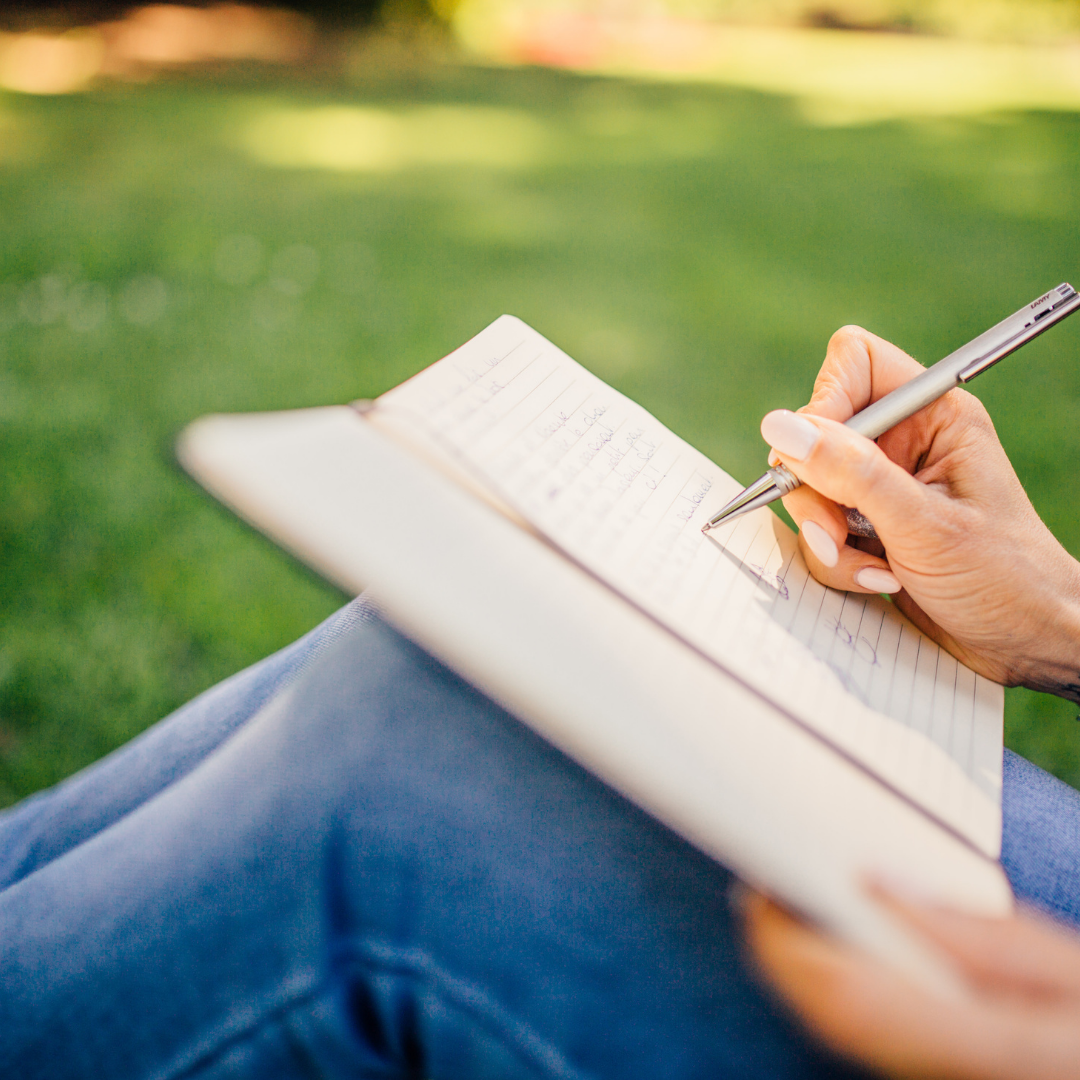 A person sat down writing in a notepad