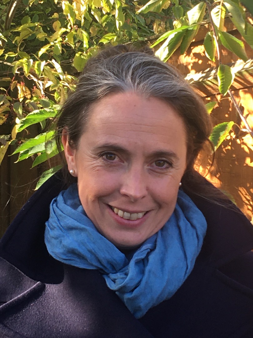 Headshot of a white woman with brown grey hair smiling into the camera