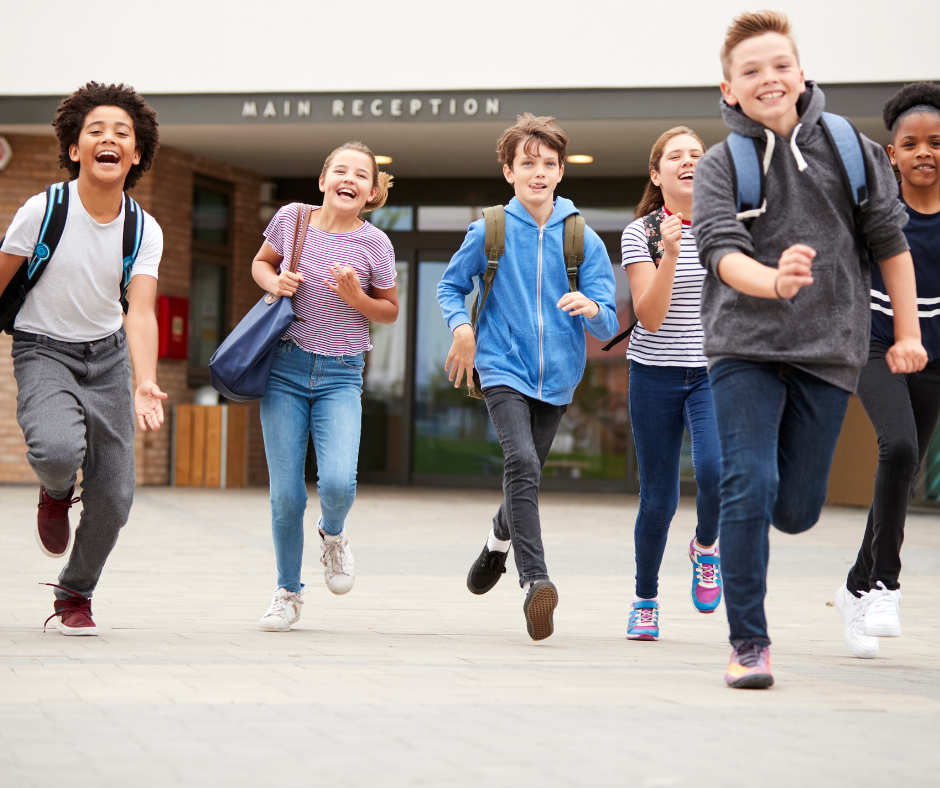 A group of young people run out of school smiling