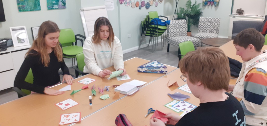 Four young people sit at a table crafting together