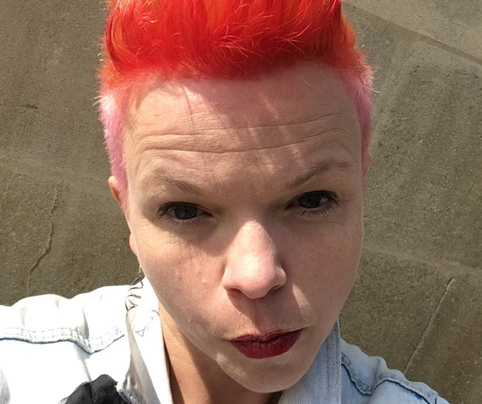 A selfie of a white woman with orange quiffed hair pouting at the camera.