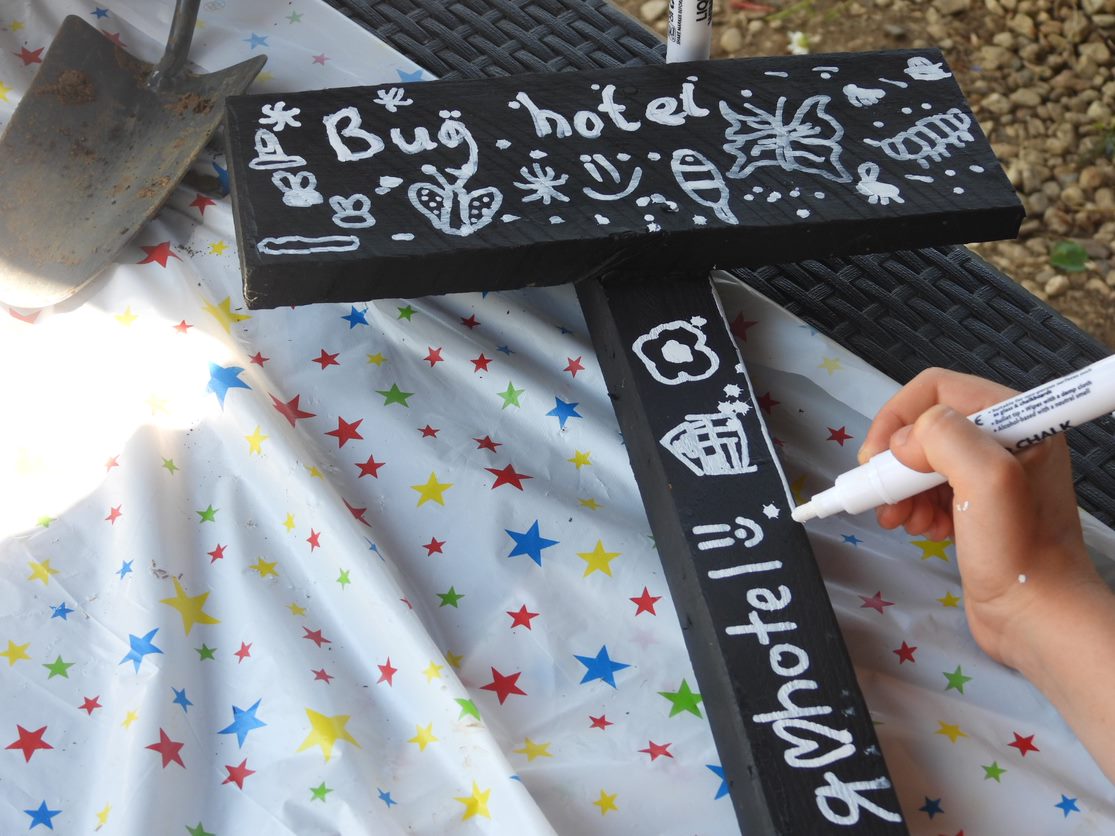 A hand creates a bug hotel sign
