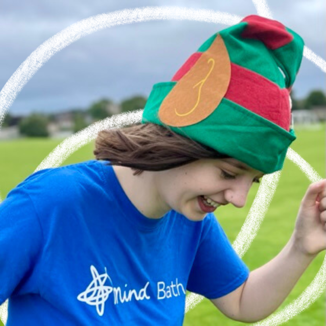 A woman wearing a Bath Mind t-shirt and elf hat running
