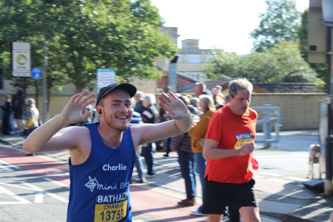 A smiling white man with a Bath Mind vest on runs Bath Half marathon.