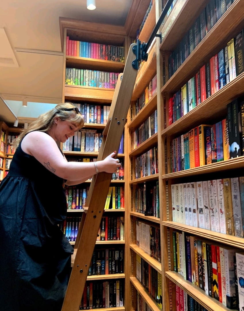 A woman climbs a staircase in a library.
