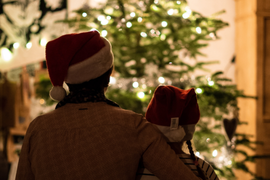 A father and son sat facing their Christmas tree