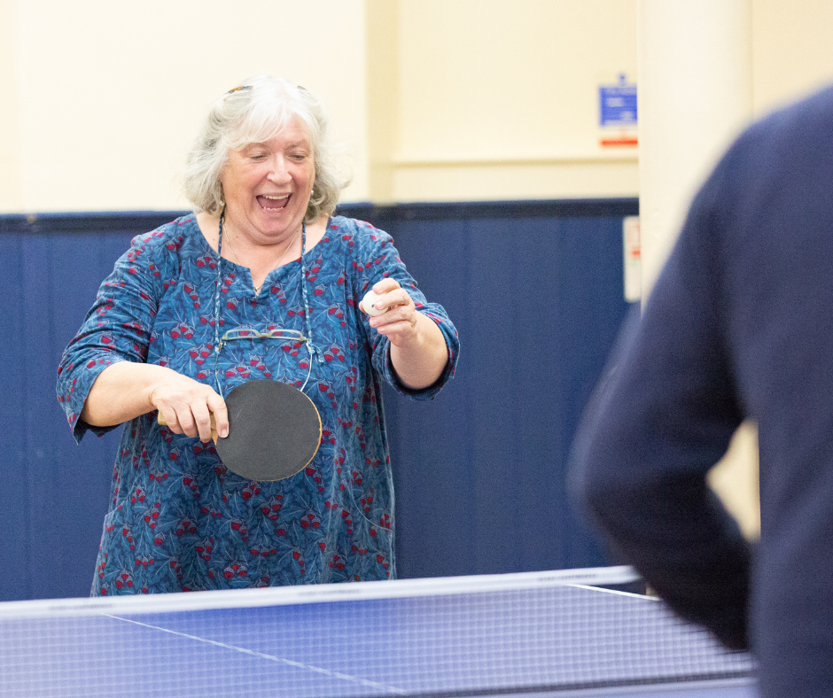 A woman plays table tennis and is smiling