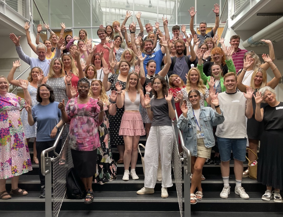 A group of people on some steps smiling with their hands in the end.