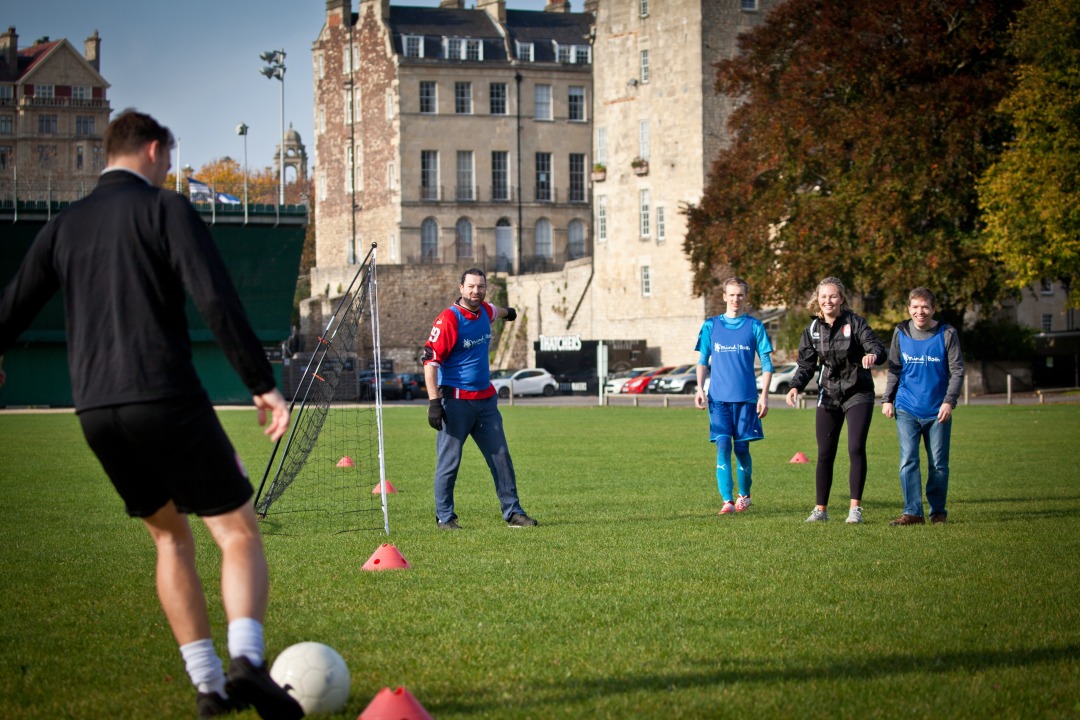 A group of people in Bath Mind vests playing football.
