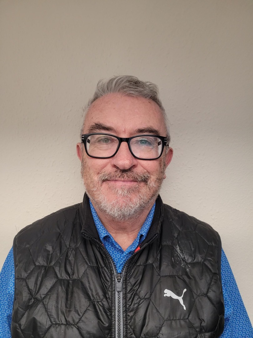 A white man with grey hair and beard and glasses,