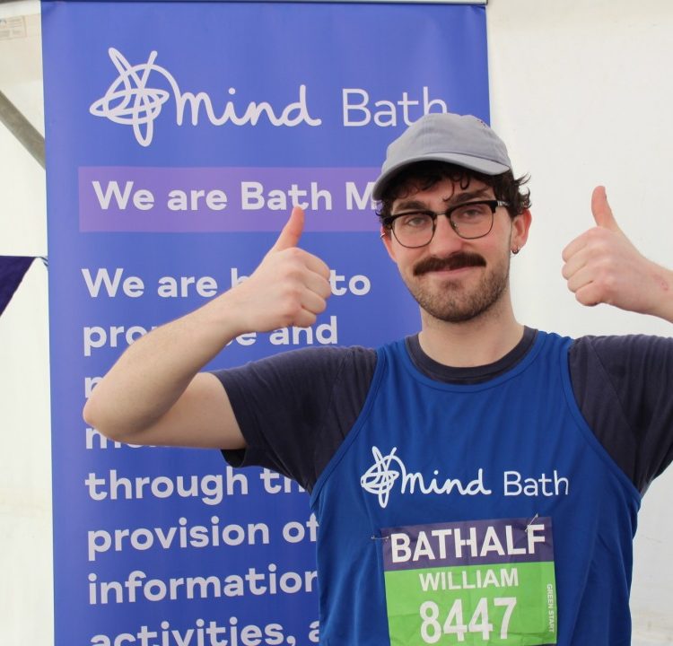 A runner wearing a Bath Mind vest smiles proudly after completing a half marathon