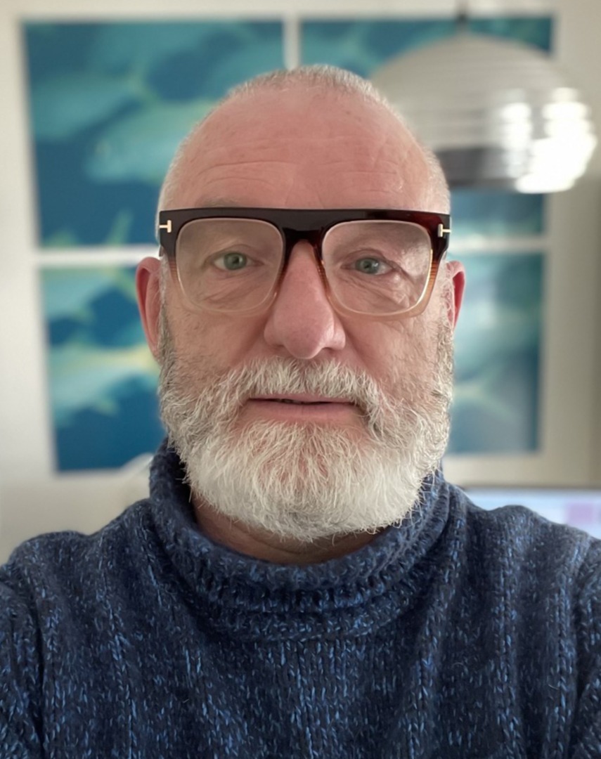 A portrait of a white man with a white beard and glasses