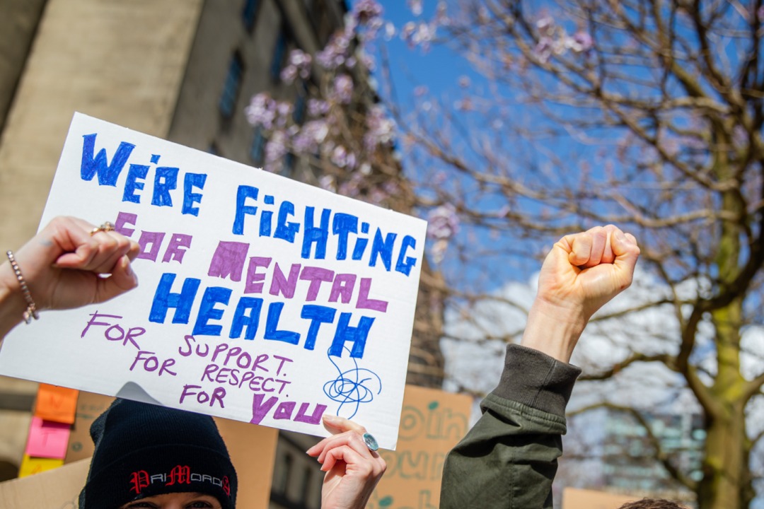 Someone holds a placard that reads 'we're fighting for mental health'