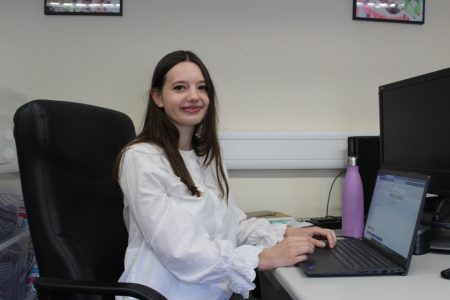 A woman sat at a computer smiling