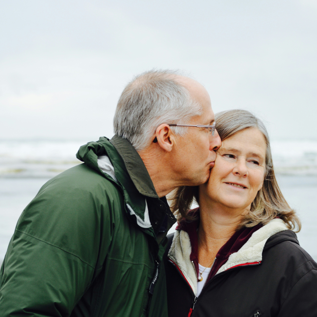 an elderly couple by the sea kissing