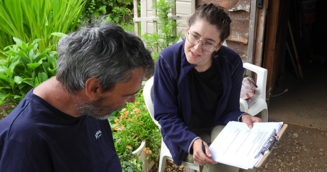 A woman sits with a man doing a referral form