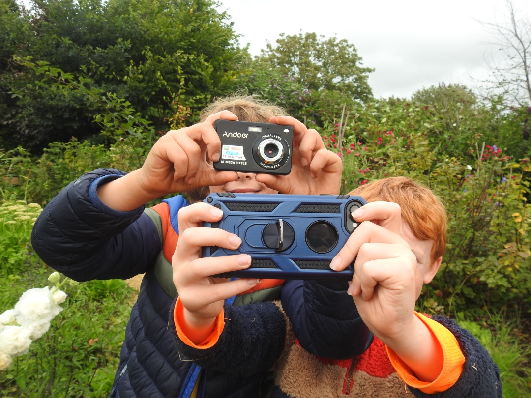 Two boys holding cameras outside