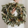 a hand holding a festive wreath