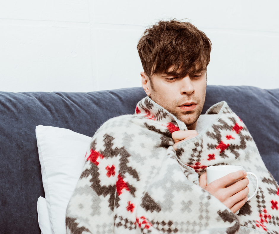 A man wrapped in a blanket drinking from a mug