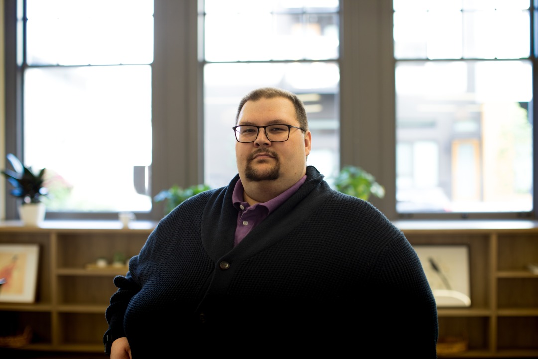 A man earing glasses and a navy cardigan