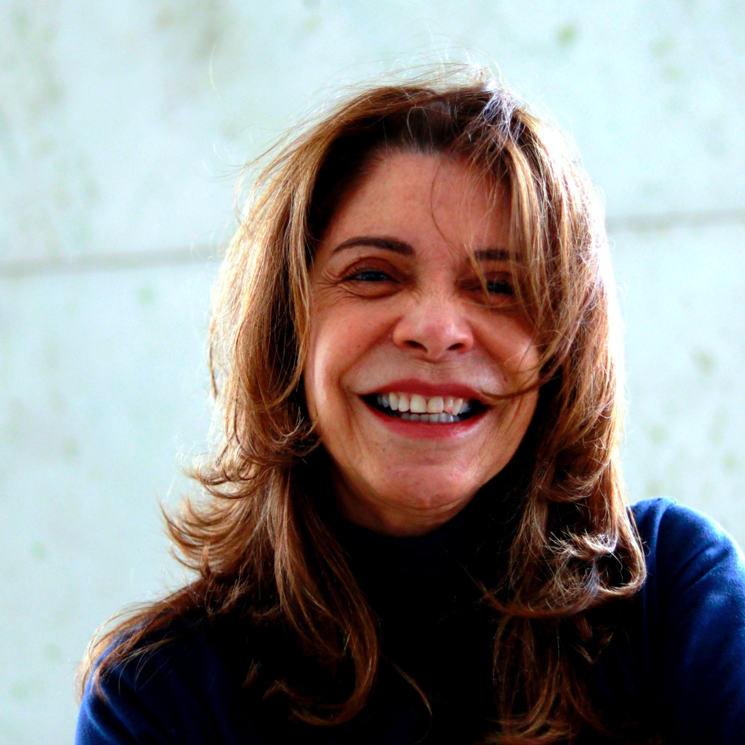 A woman with brown hair wearing a black jumper smiling into the camera