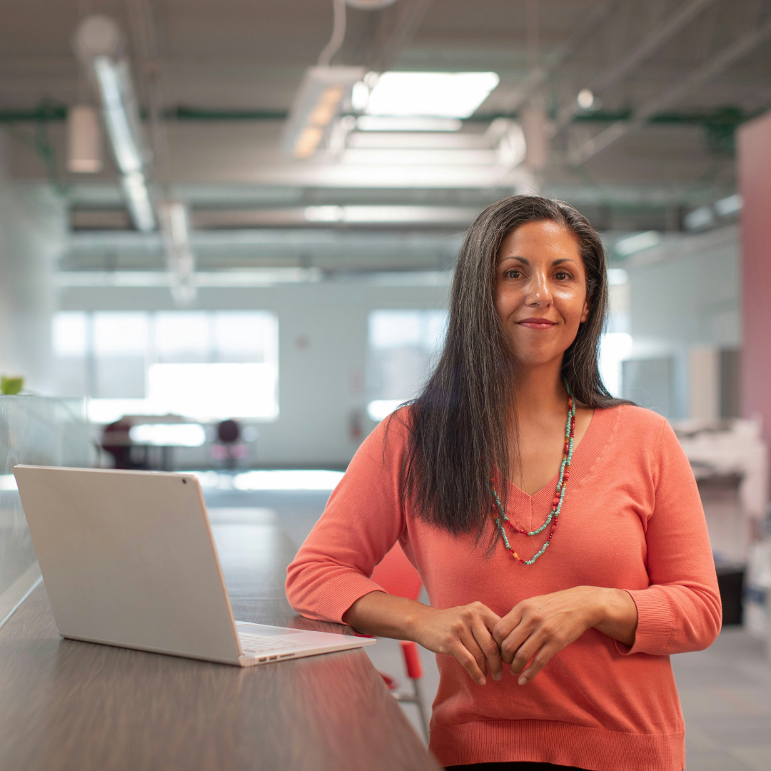 A woman stood beside a laptop